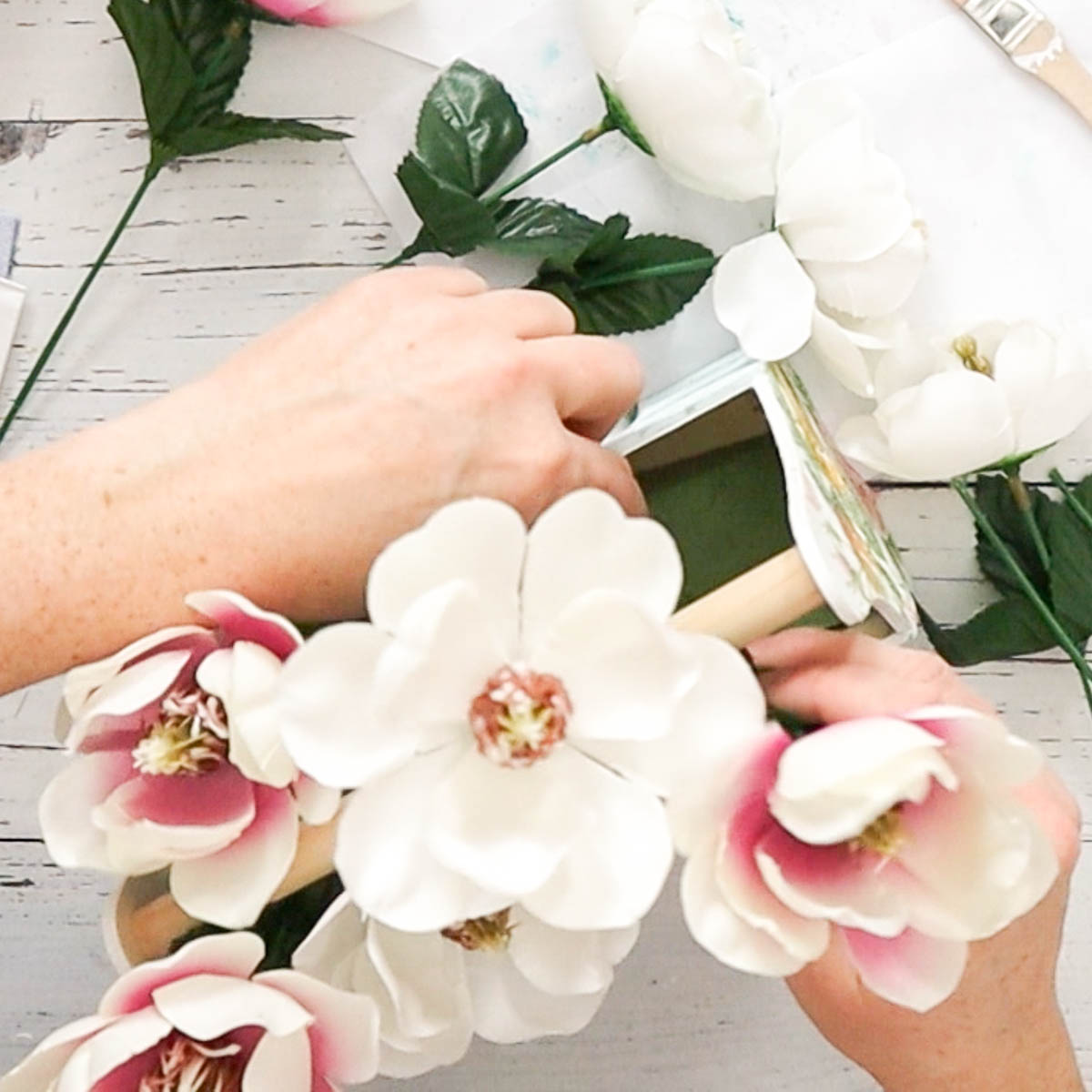 Inserting faux Magnolia flowers into the floral foam.