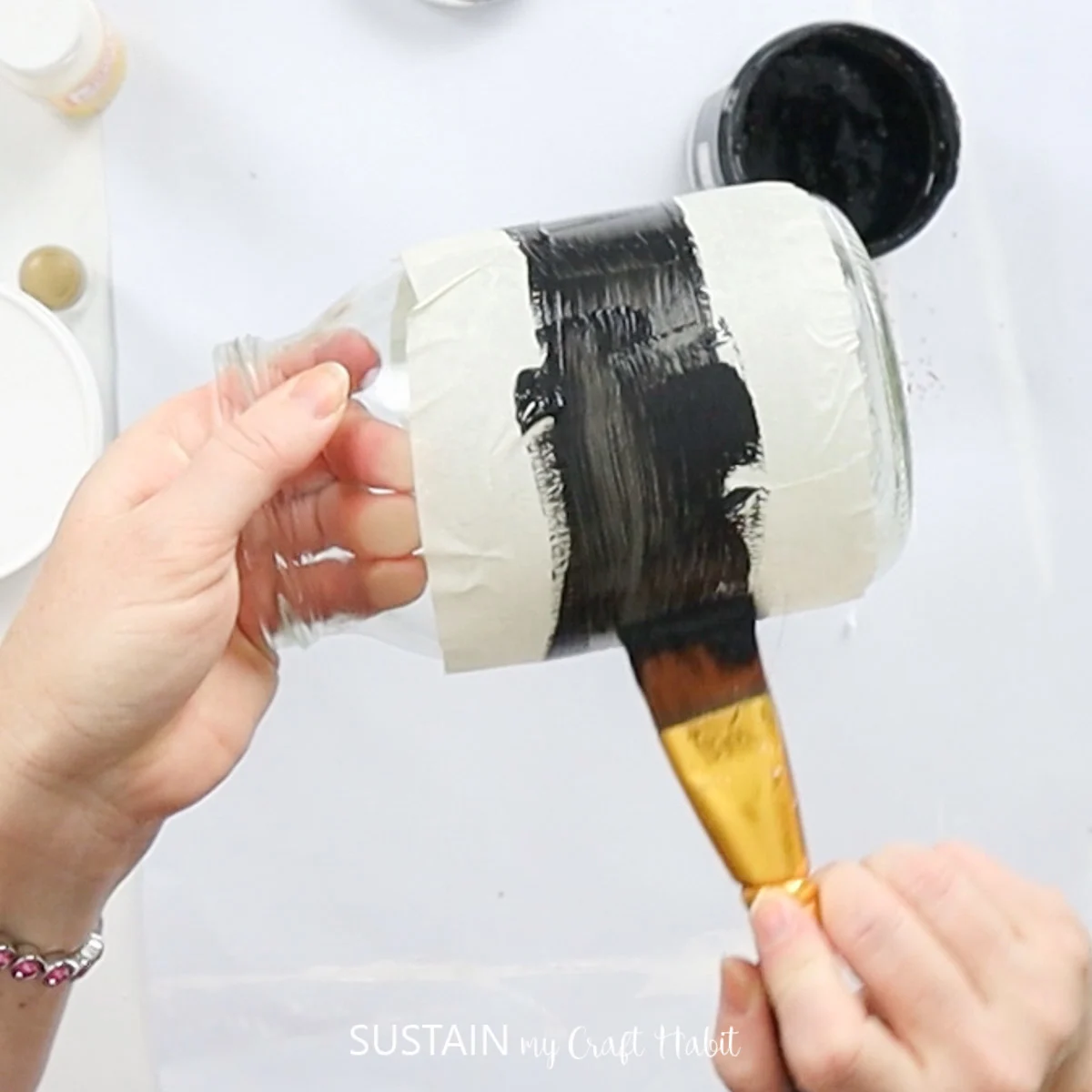 Painting the middle of a mason jar black.
