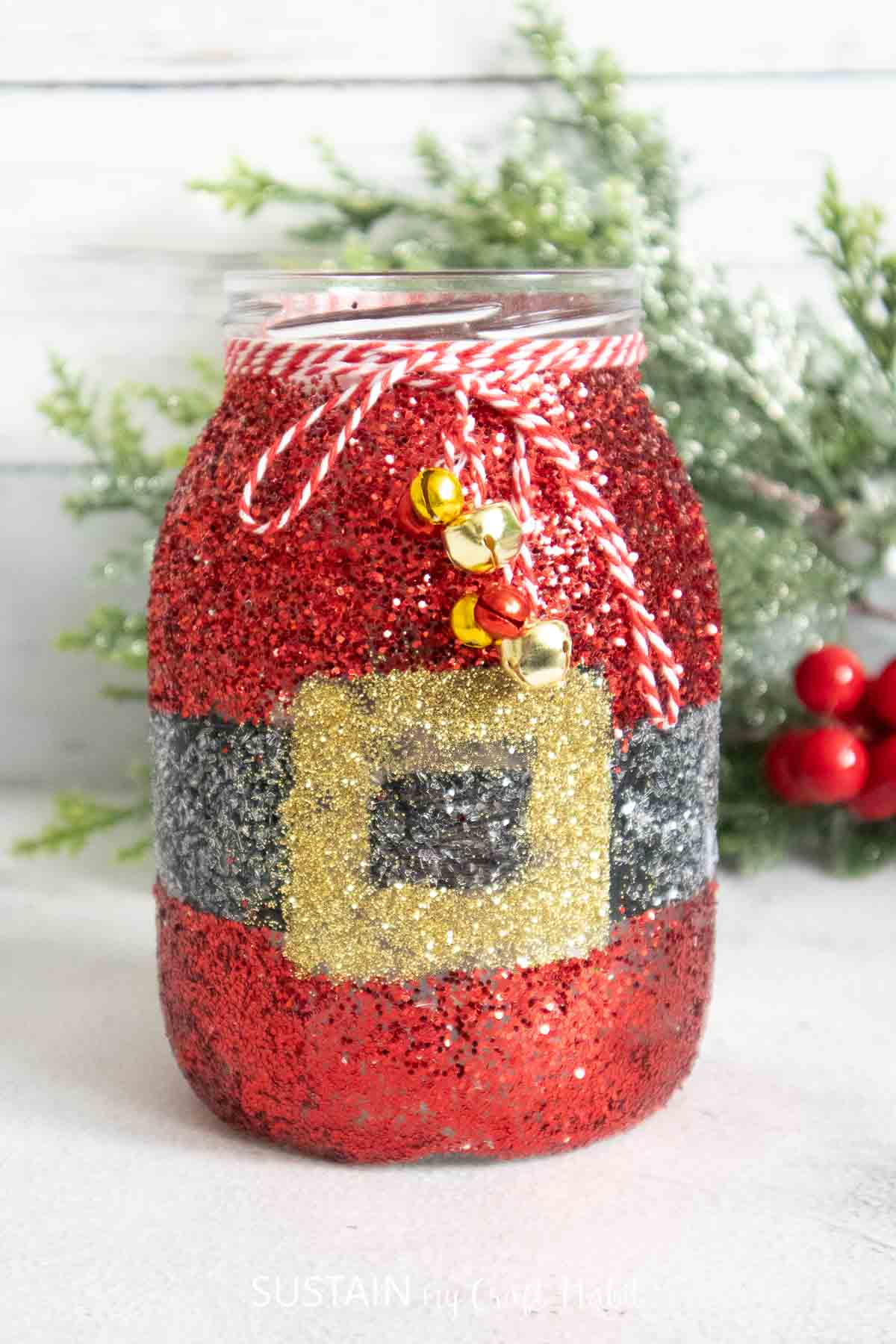 Glittering Santa Claus mason jar craft with twine and bells.
