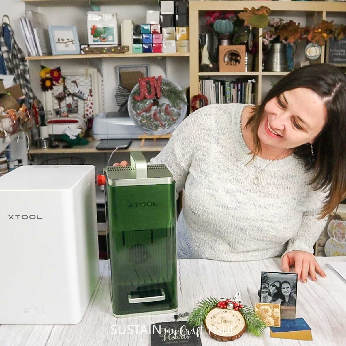 Woman looking at the xTool F1 portable laser and cutting machine with several completed porjects in the foreground.