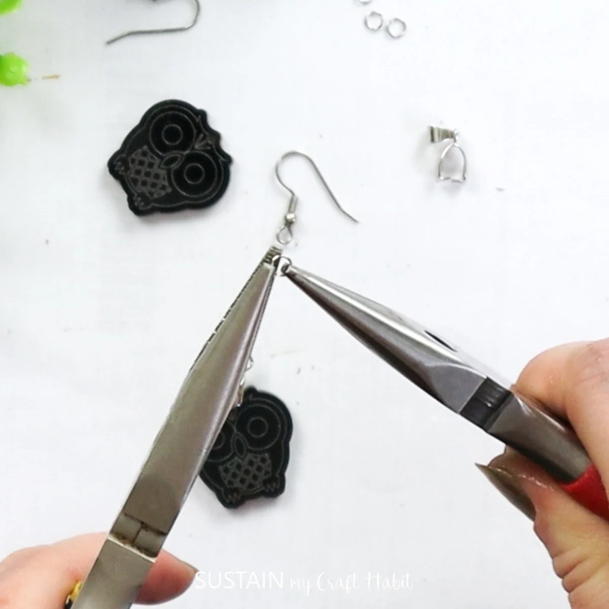 Using pliers to open a jewelry eyelet.