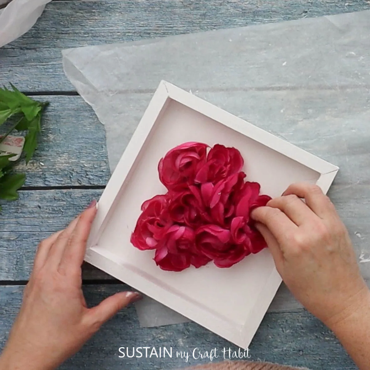Gluing faux flowers to form a heart shape.