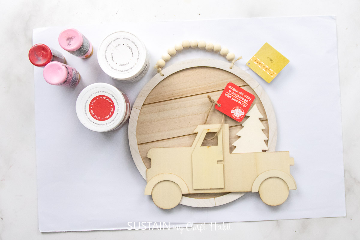 Materials needed to make a Valentine's truck craft including a sign, wood truck and paint.