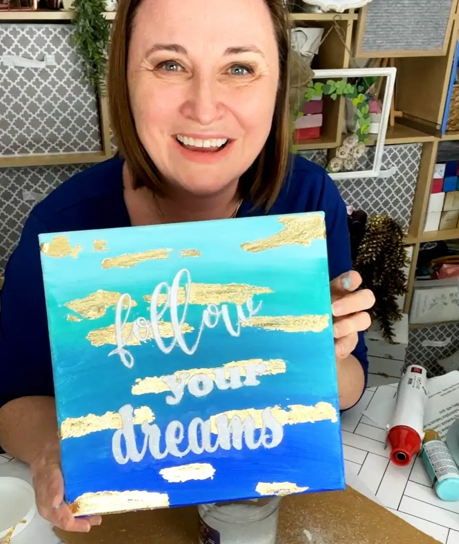 Woman holding a beach themed canvas painting.