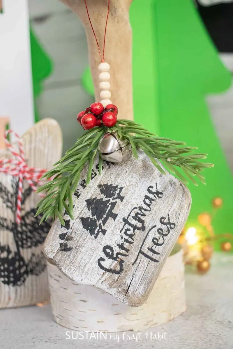 Driftwood ornament decorated with chalk couture paint, greenery and bells.