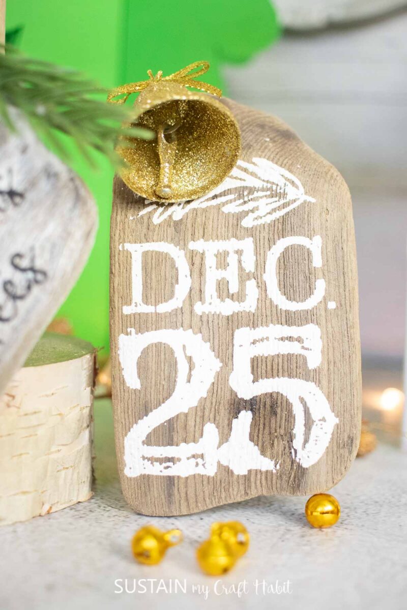 Driftwood ornament decorated with chalk couture paint and a bell.