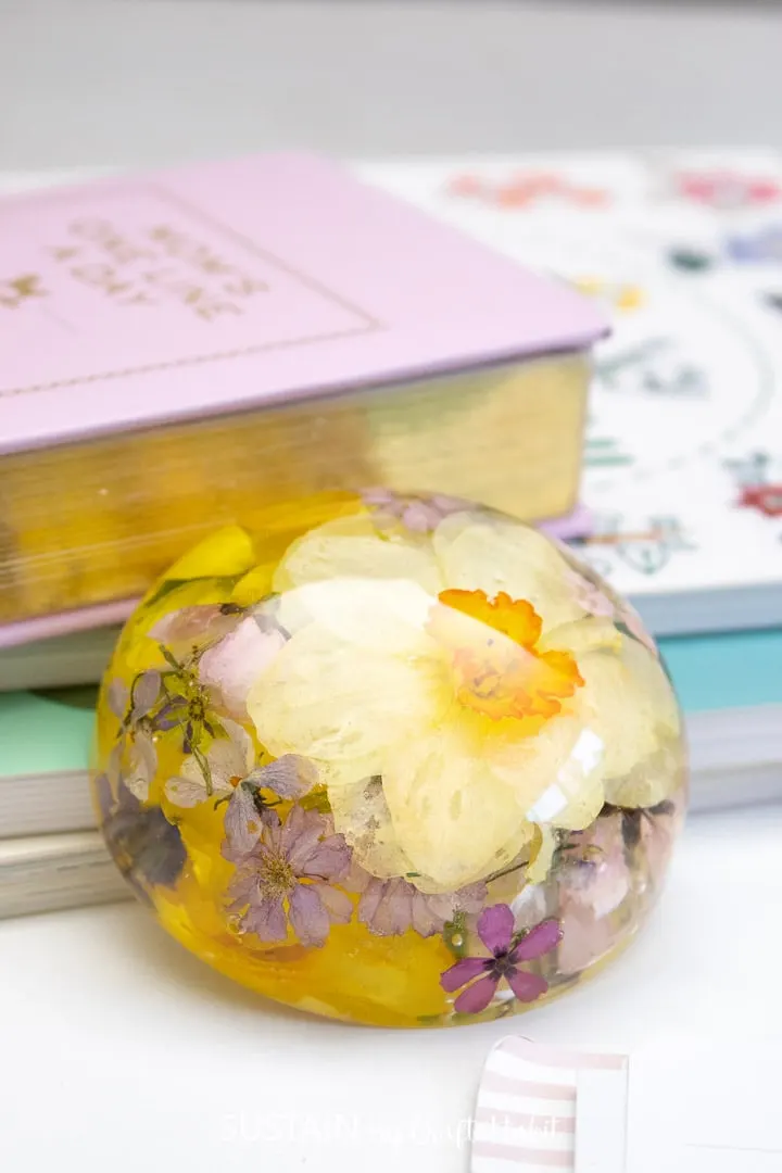Daffodil paperweight leaning against books.