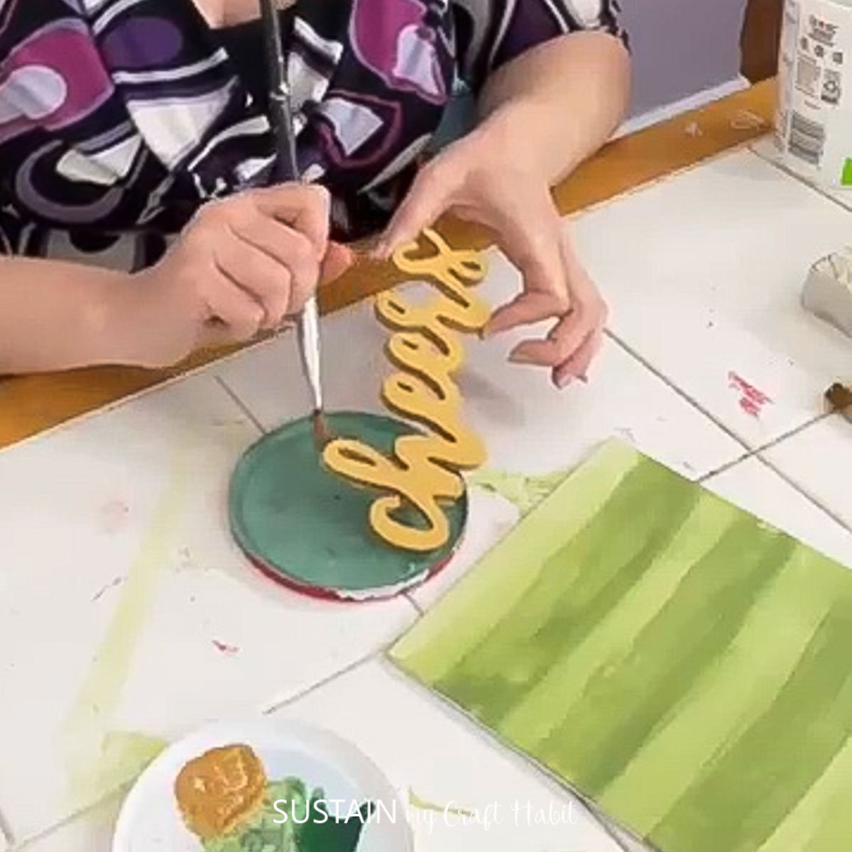 Painting a wooden cheers sign with gold paint.