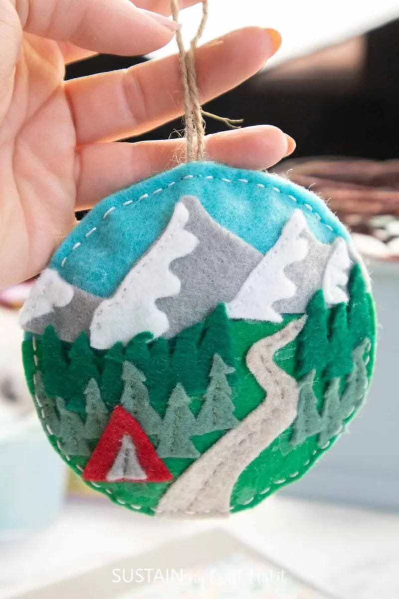 Hand holding a felt travel ornament.