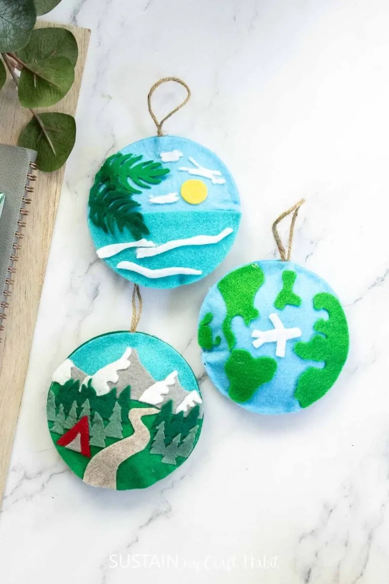 Three felt travel ornaments on a desk.