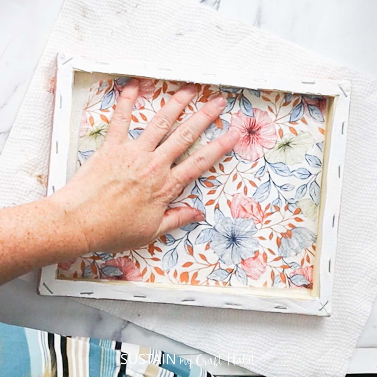 Gluing a paper napkin onto the back of a canvas.