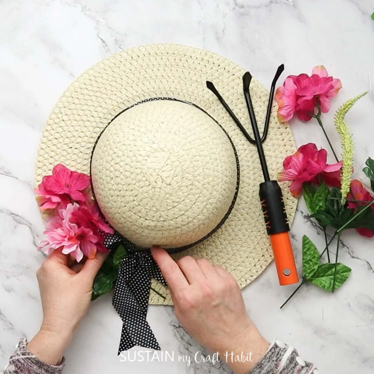 Attaching faux flowers to the straw hat.