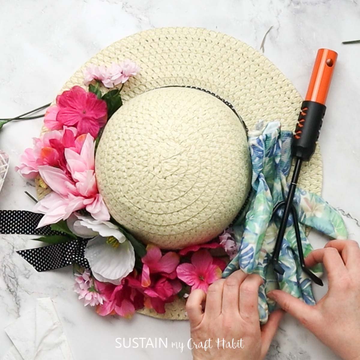 Attaching gardening tools to the straw hat. 