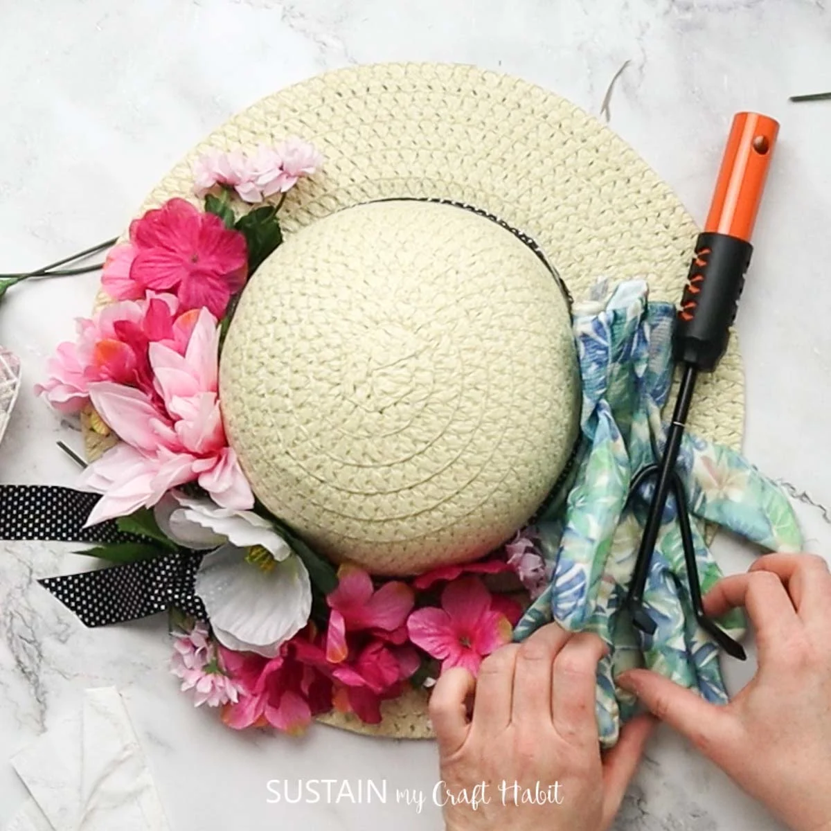 Attaching gardening tools to the straw hat.