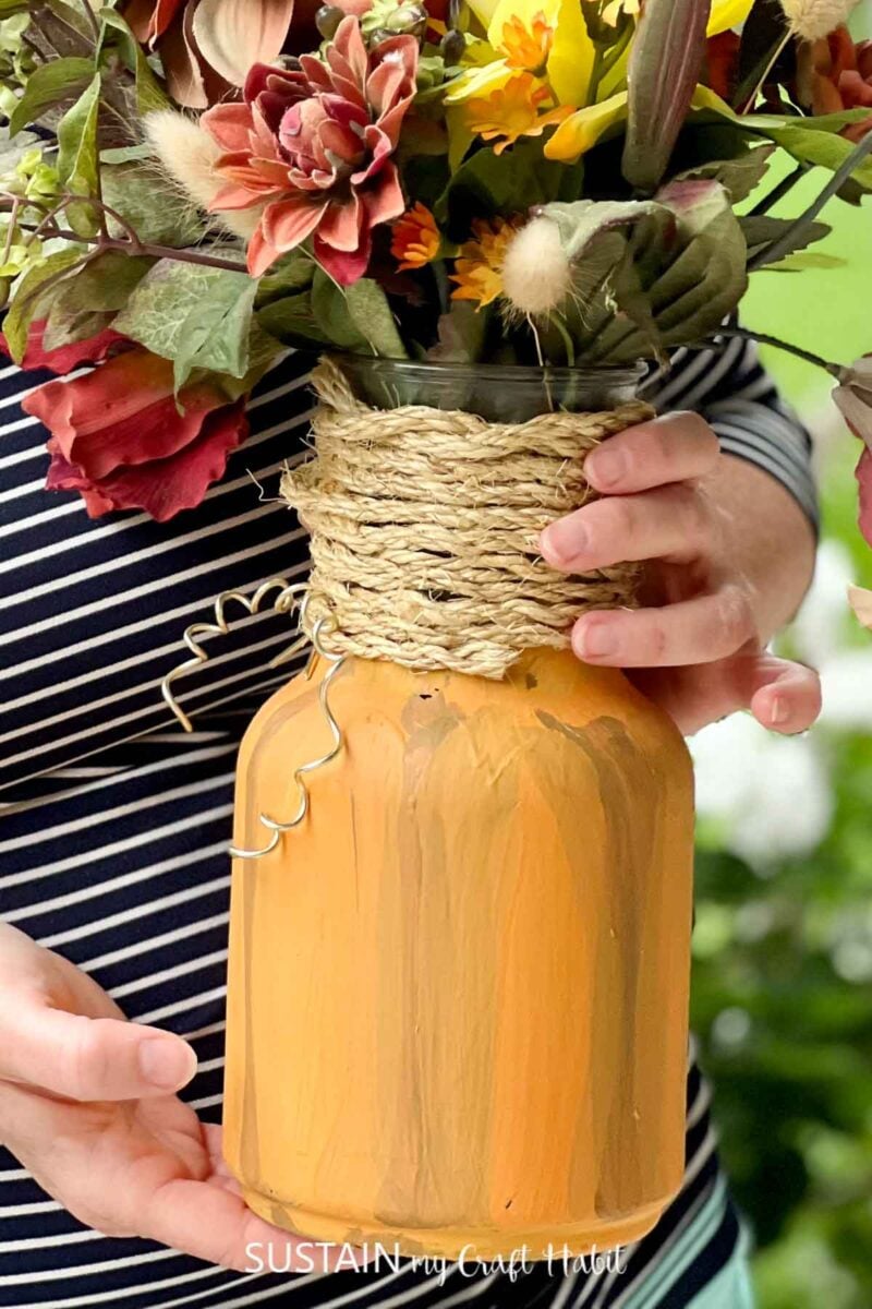 Mason jar pumpkin filled with flowers.