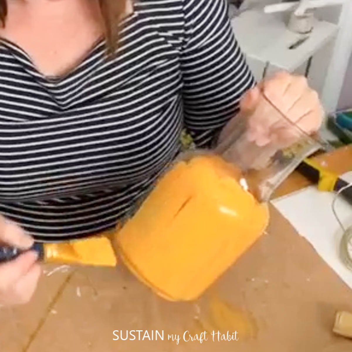 Painting a glass jar orange.