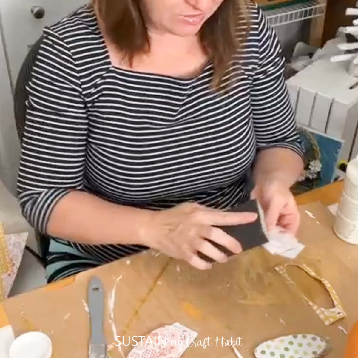 Woman removing excess paper with a sanding block. 