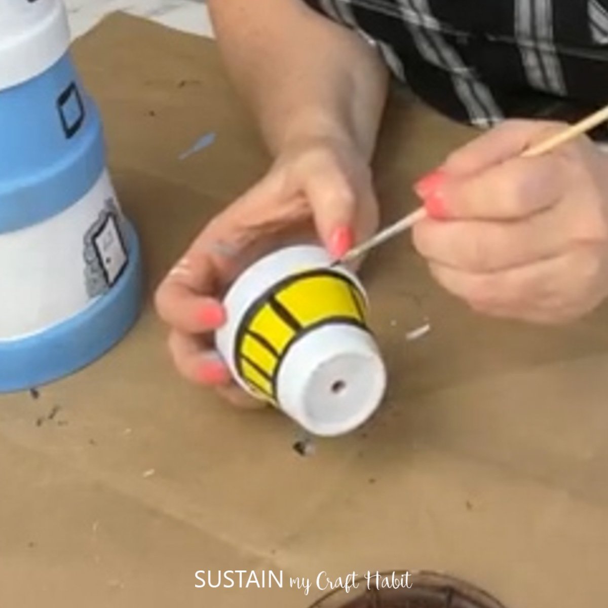 Painting black windows onto a clay pot.