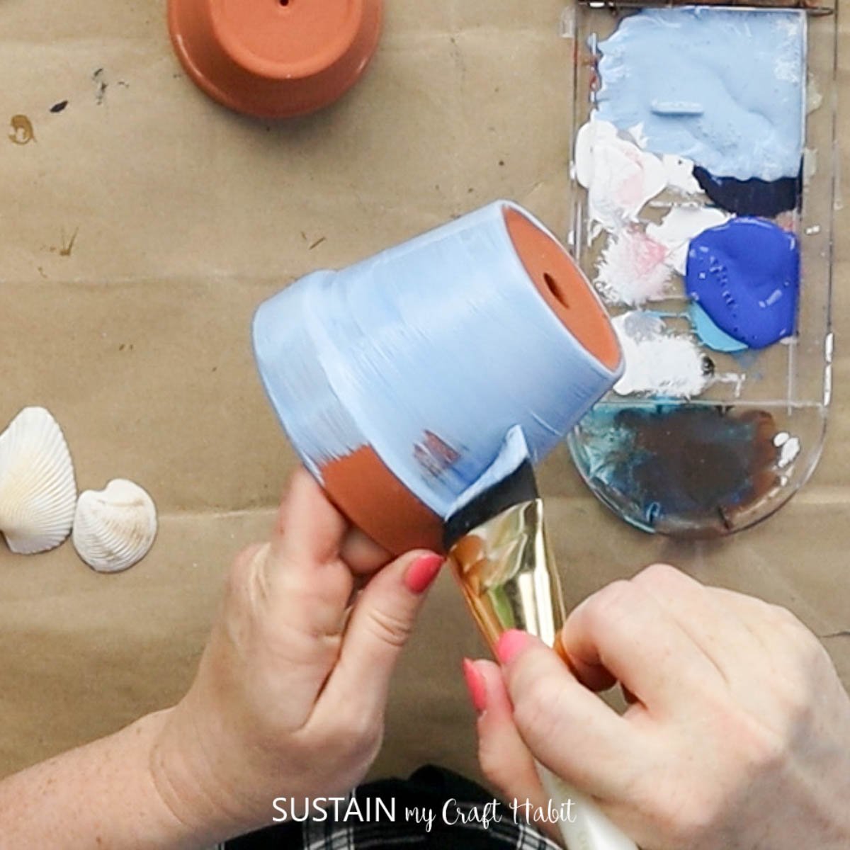 Painting a clay pot blue.