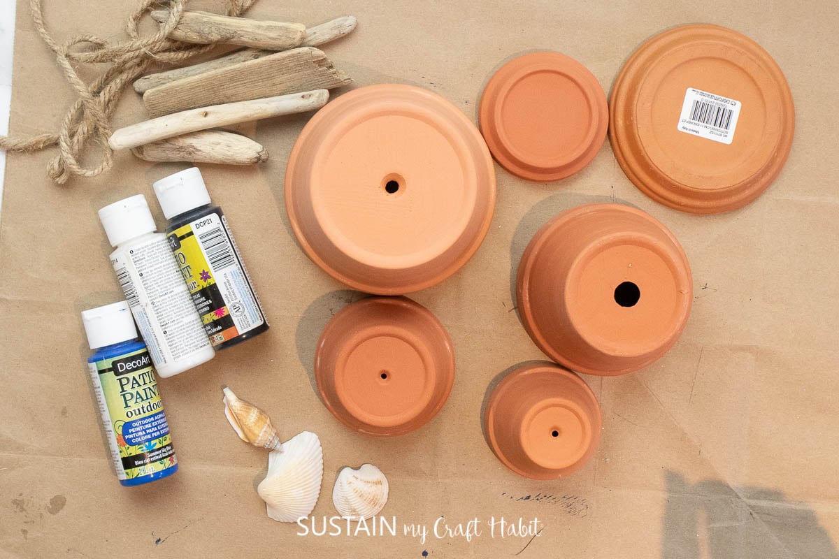 Materials needed to make a lighthouse, including clay pots, paint and decorative embellishments.