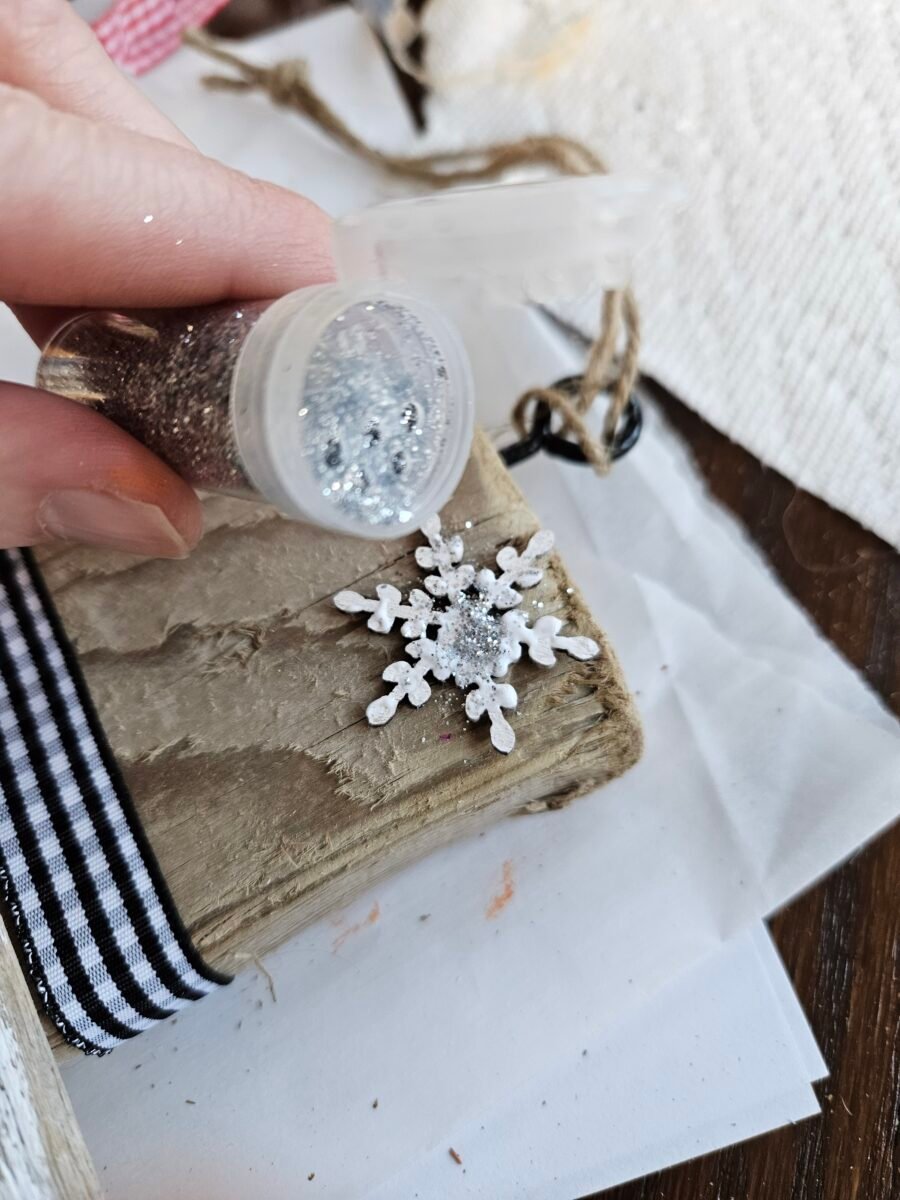 Adding glitter to a wood snowflake.