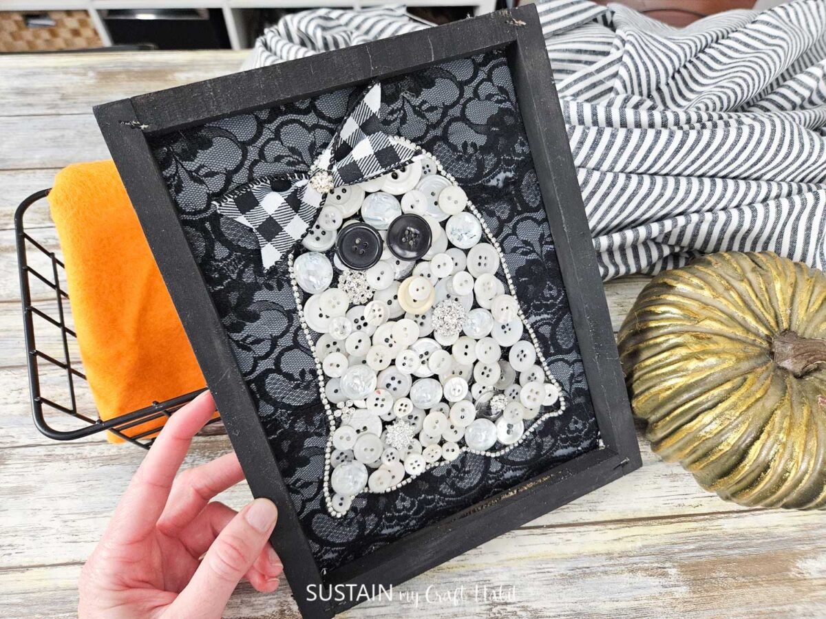 Hand holding ghost art made from buttons.