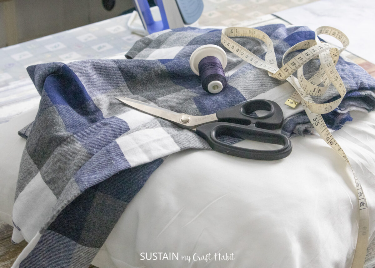 Materials needed for an envelope pillow cover, including fabric, scissors, measuring tape and thread.