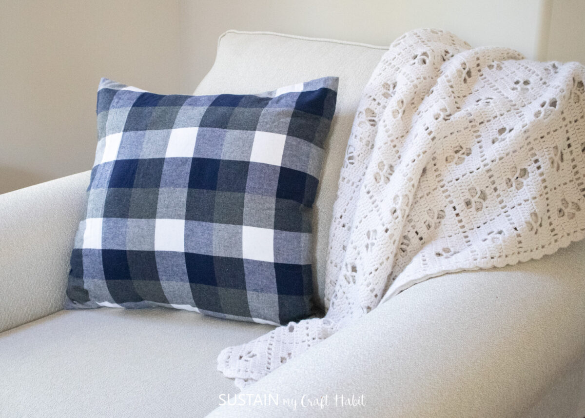 Envelope pillow cover on a couch next to a blanket.