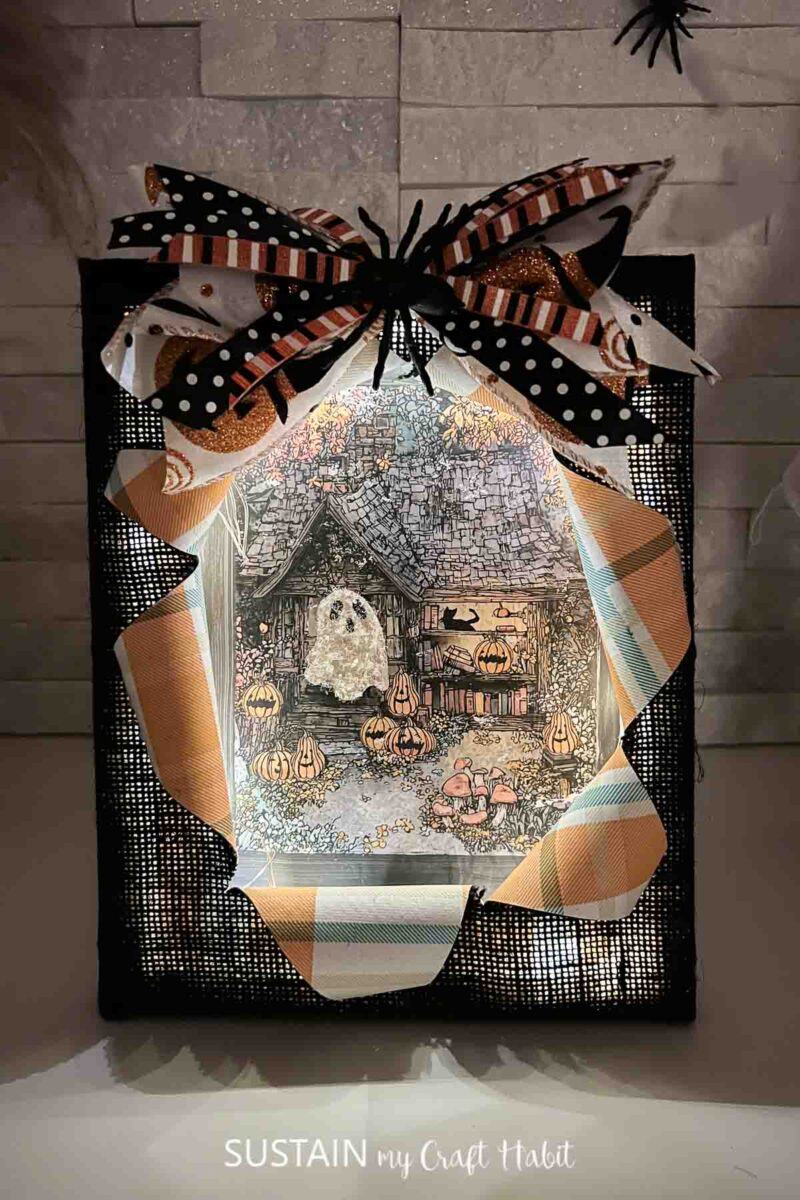 Busted canvas Halloween craft with a ghost image and lights.