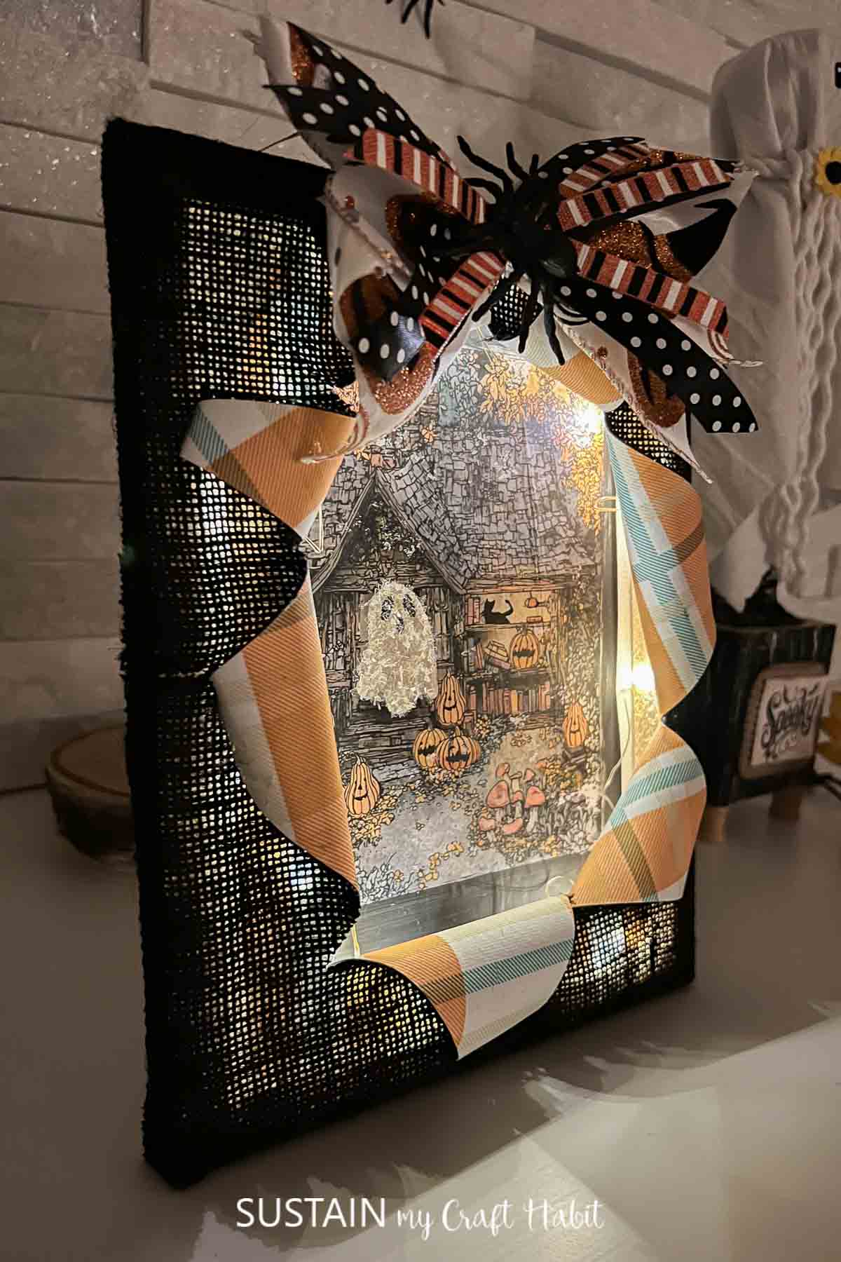 Busted canvas Halloween craft with a ghost image and lights.