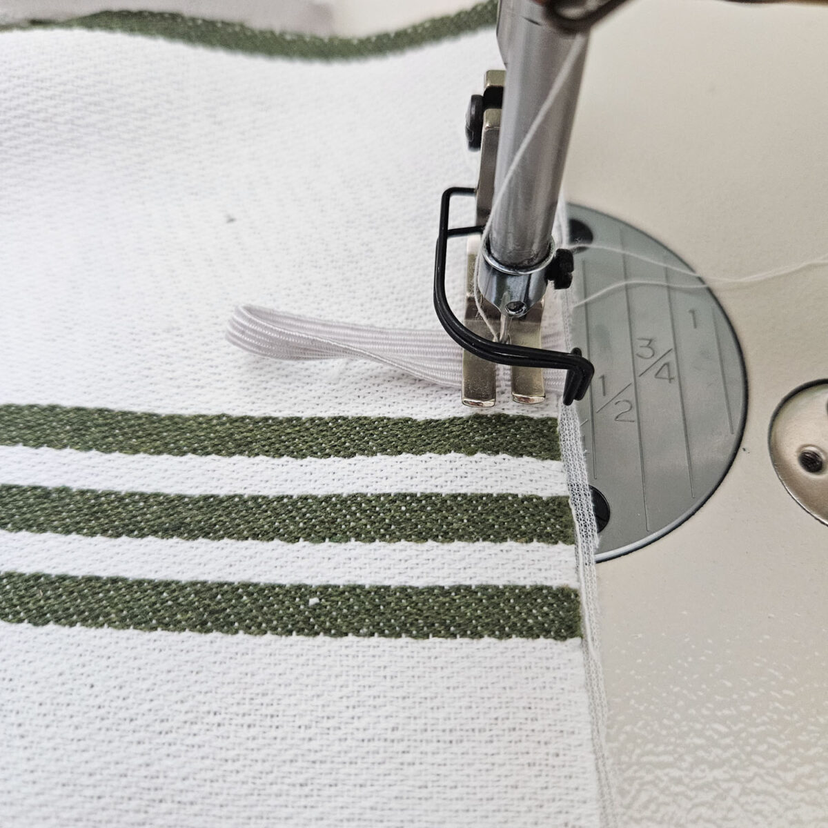 Sewing an elastic loop onto the edge of the tea towel.