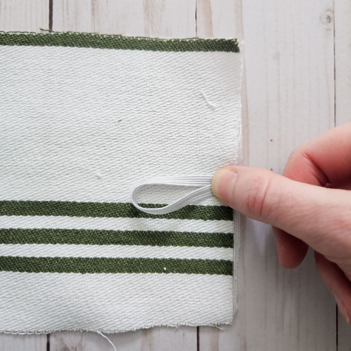 Positioning an elastic loop onto the edge of a tea towel.