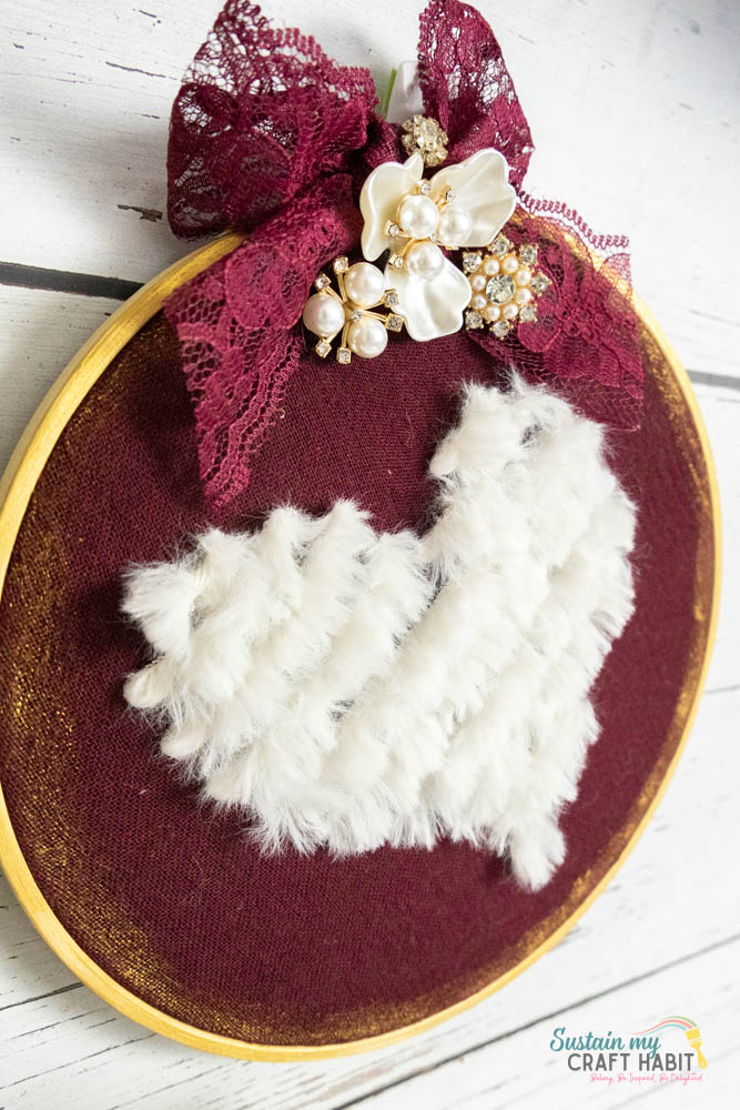 Embroidered yarn heart decor hanging on a wall.