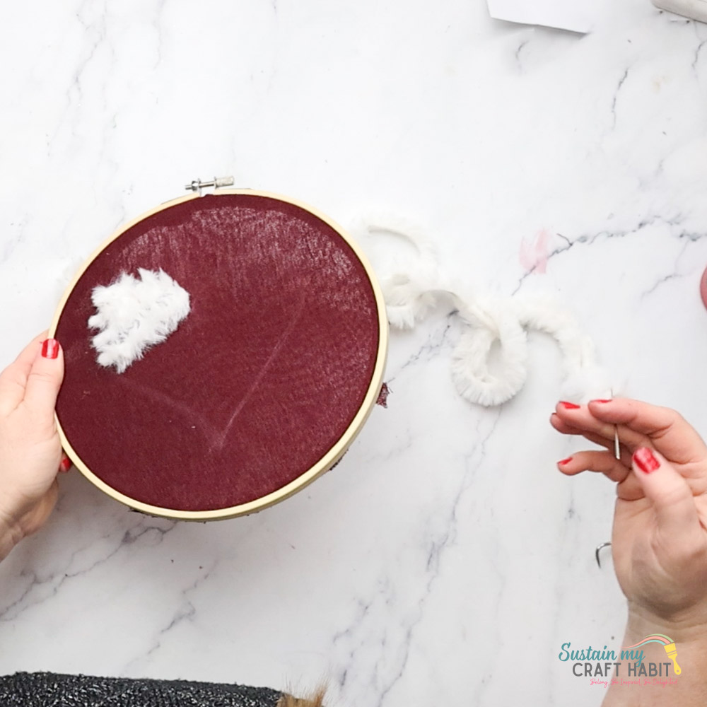 Threading a needle with yarn through the fabric.