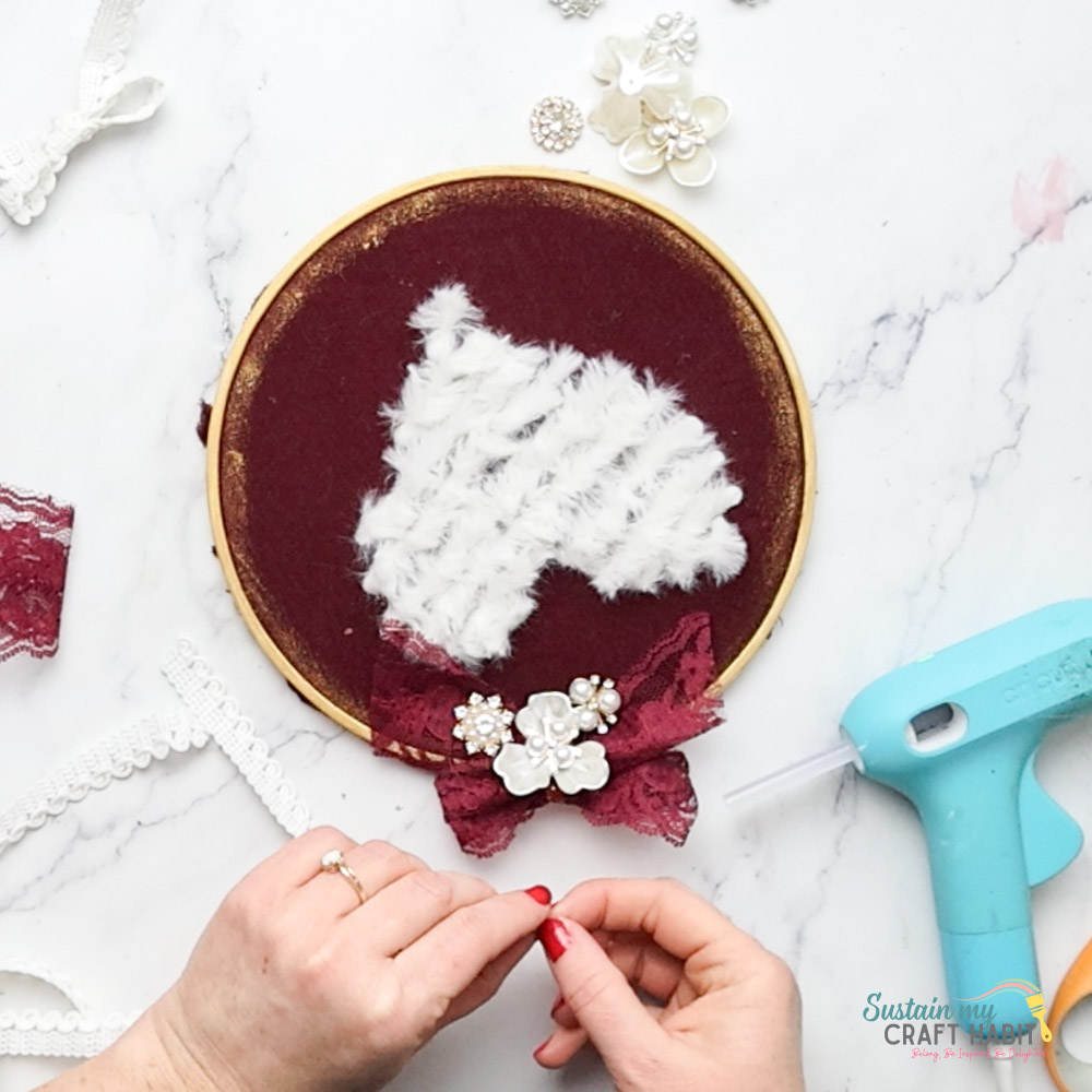 Hot gluing embellishments onto the embroidery hoop.