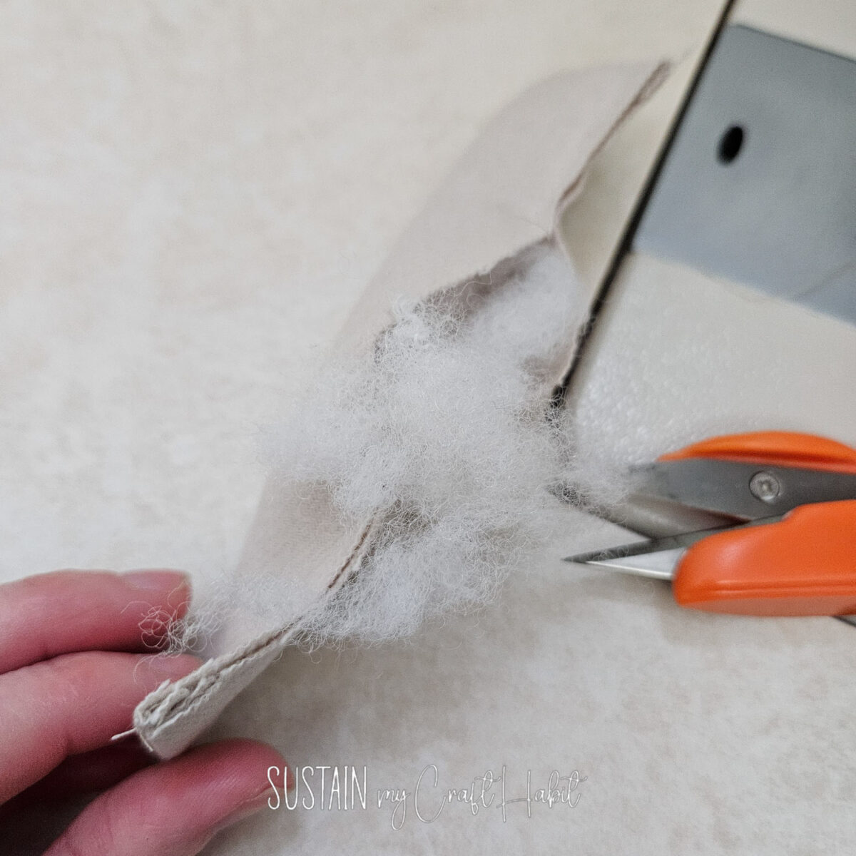 Filling small piece of fabric with stuffing.