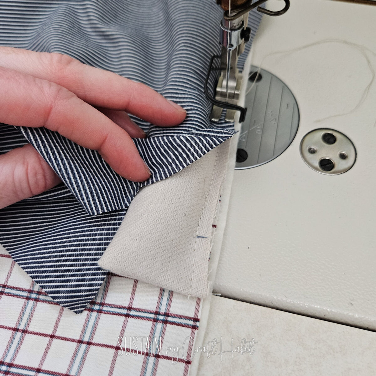 Sewing machine stitching fabric together.
