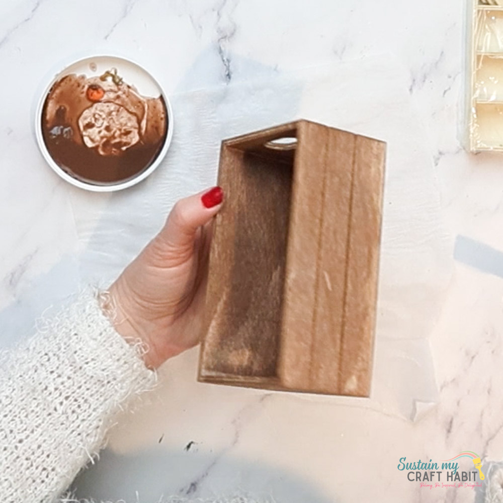 Painting a wooden box with brown paint. 