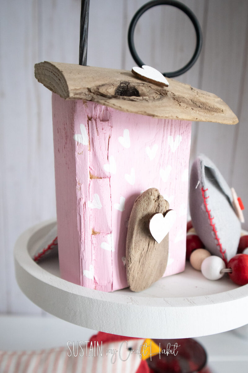 Scrap wood house shelf sitter placed on a tray with decor.