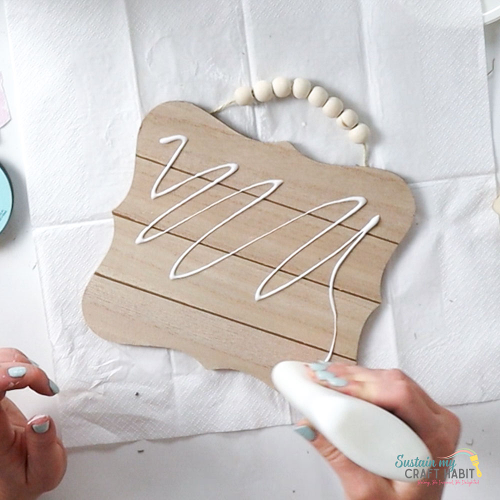 Adding glue to a wooden plaque.