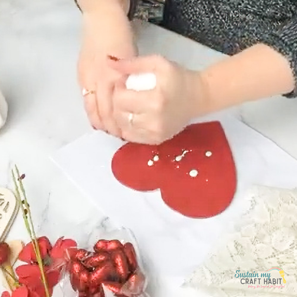 Adding glue to red painted heart.
