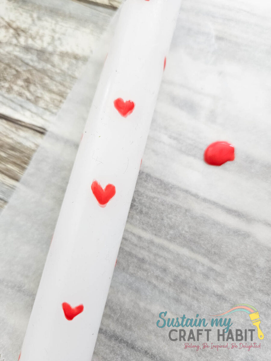 Painting red hearts onto candles.