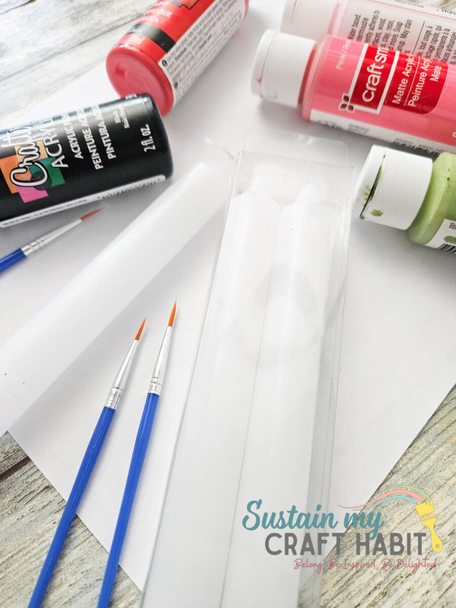 an assortment of paints, paintbrushes and taper candles