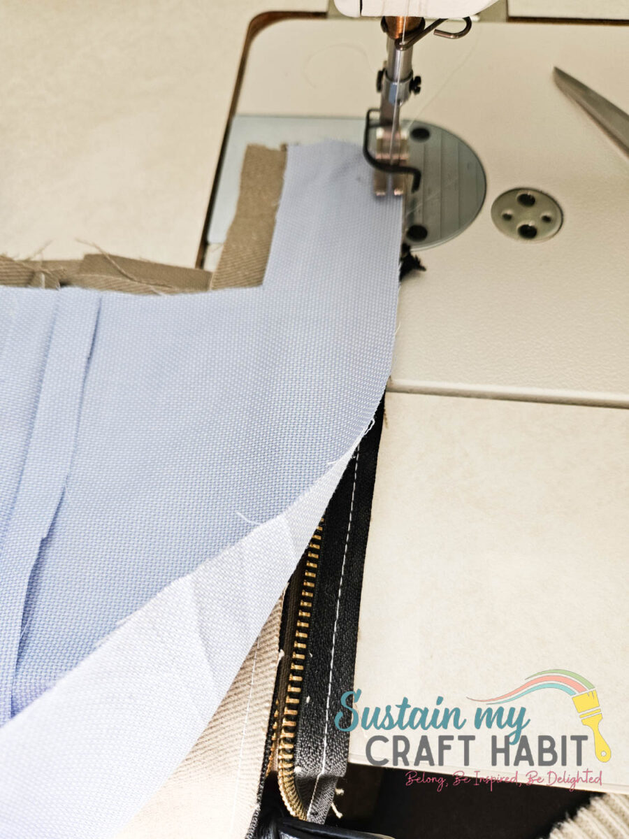 Attaching blue fabric piece to zipper.