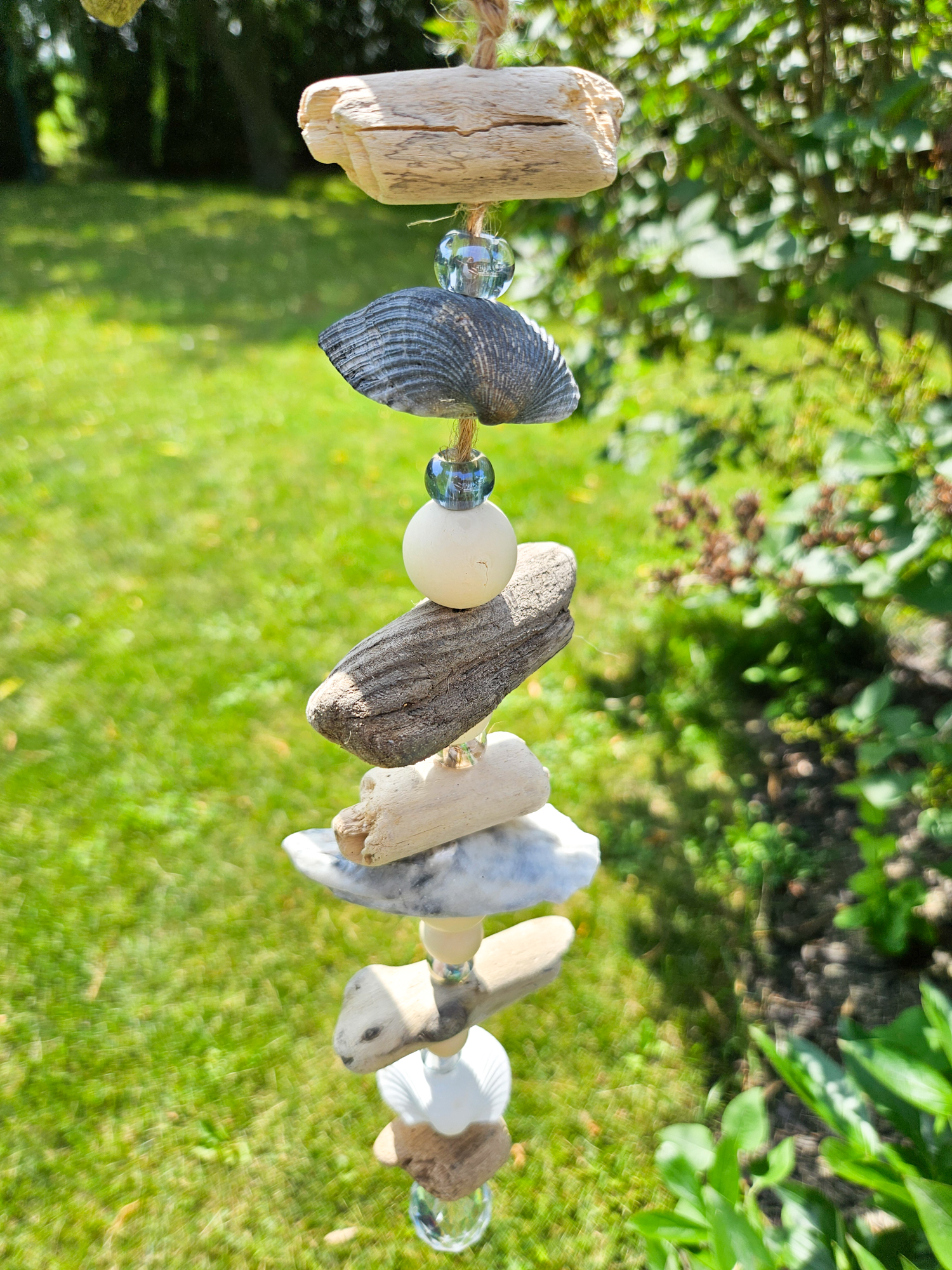 strand of driftwood, seashells and beads hanging from a tree branch