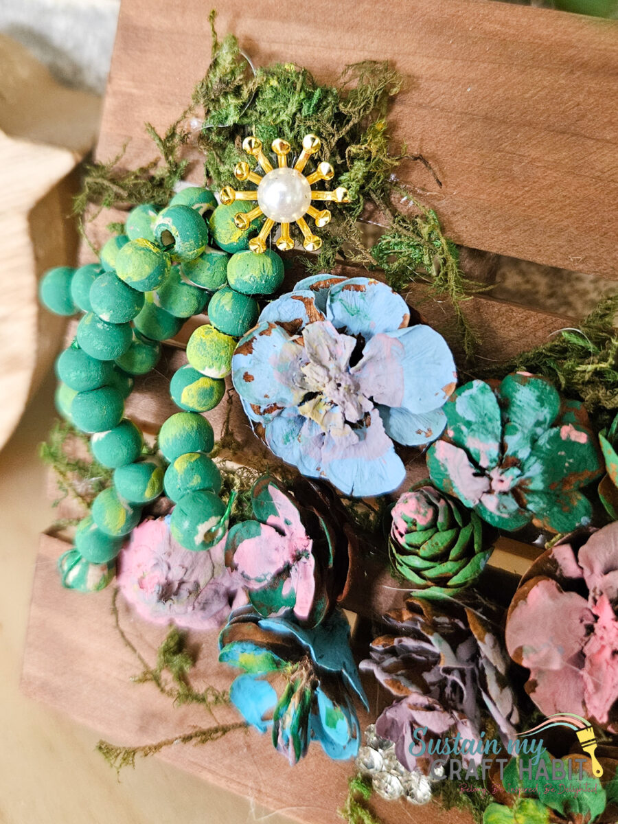 Close up of painted pinecones and embellishments.