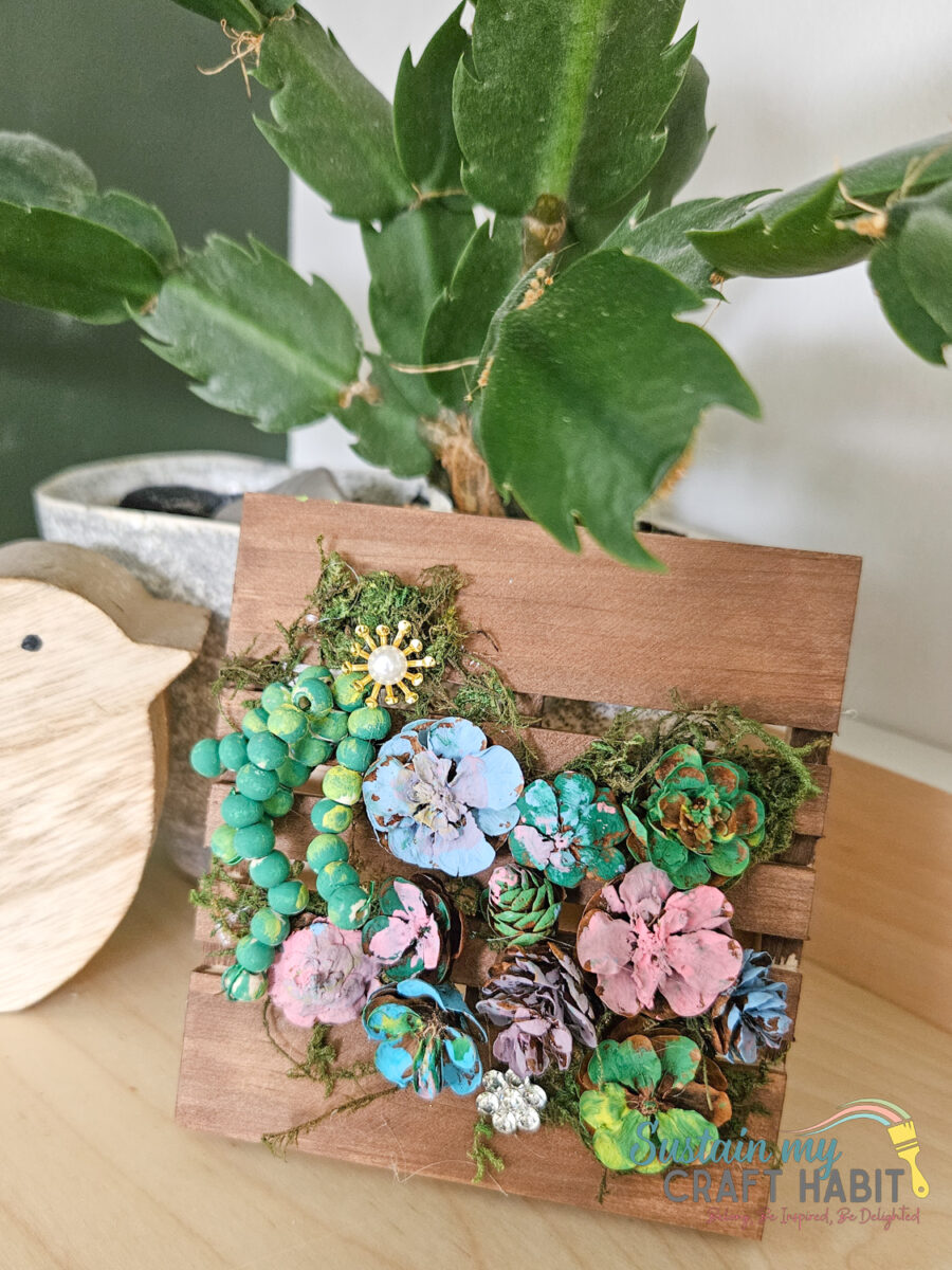 Pinecone succulent decor with embellishments on a mini pallet.